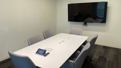Small conference room with one table, six chairs and a tv monitor
