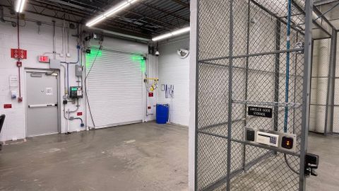 Inside a loading bay that is next to an Exit and has a caged area for good storage